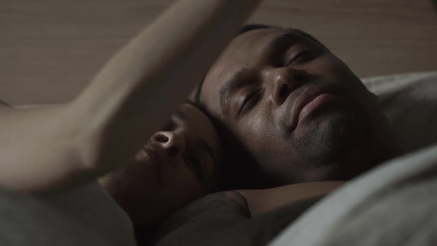 A man and woman lay in bed smiling