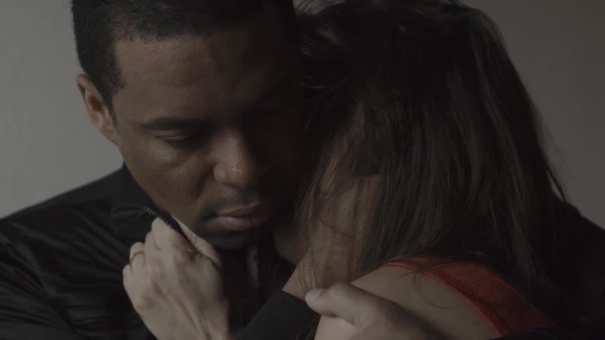 A man hugs a woman and she touches his face
