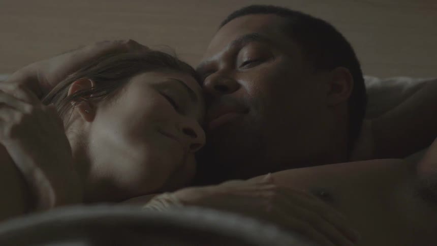 Man caressing a woman's head as they lay together in bed