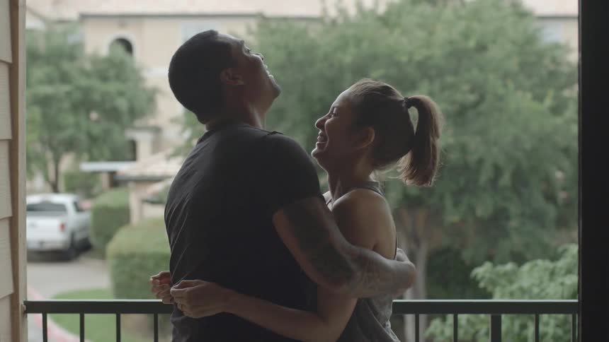 A man and woman standing on a porch playfully play punching