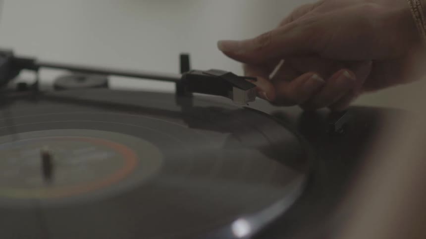 A person places a needle on a record player