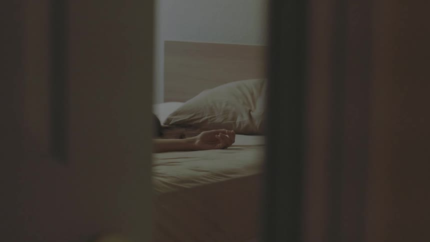 A person can be seen sleeping on a bed from a doorway