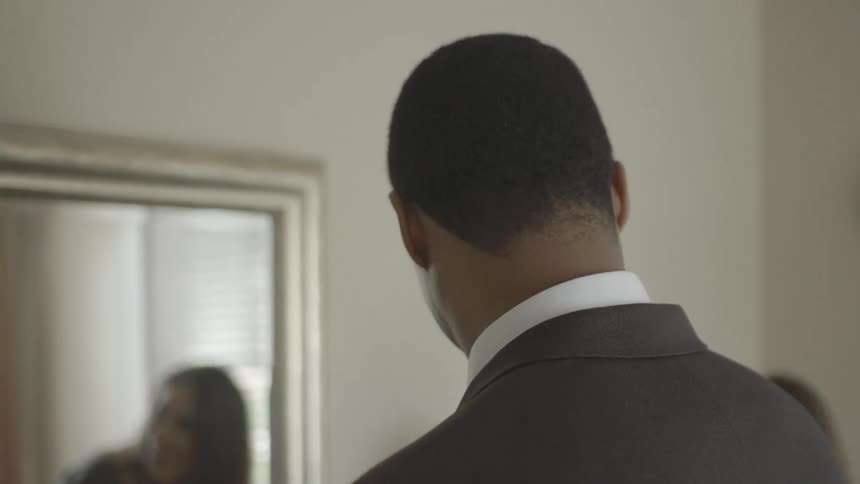 A man in a suit smiles and turns around