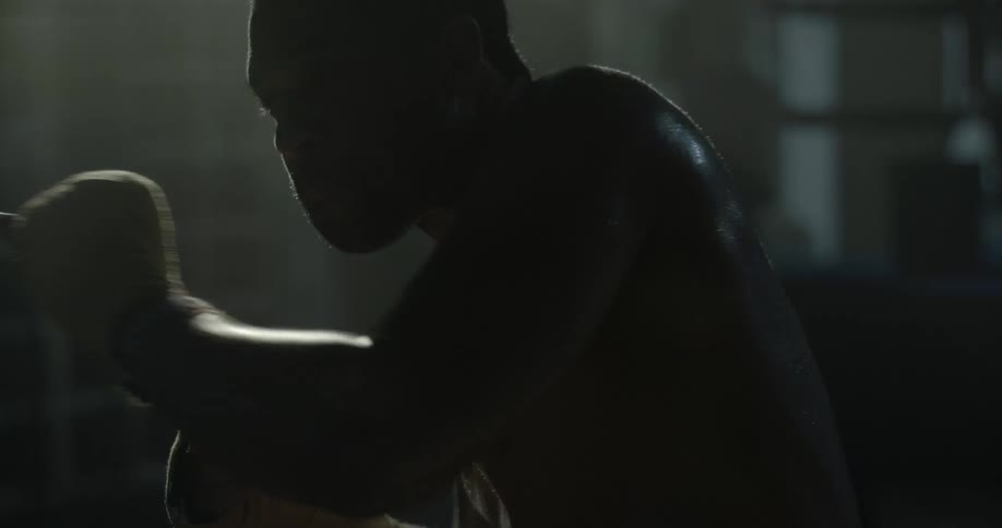 A man practicing his boxing moves in a dark gym