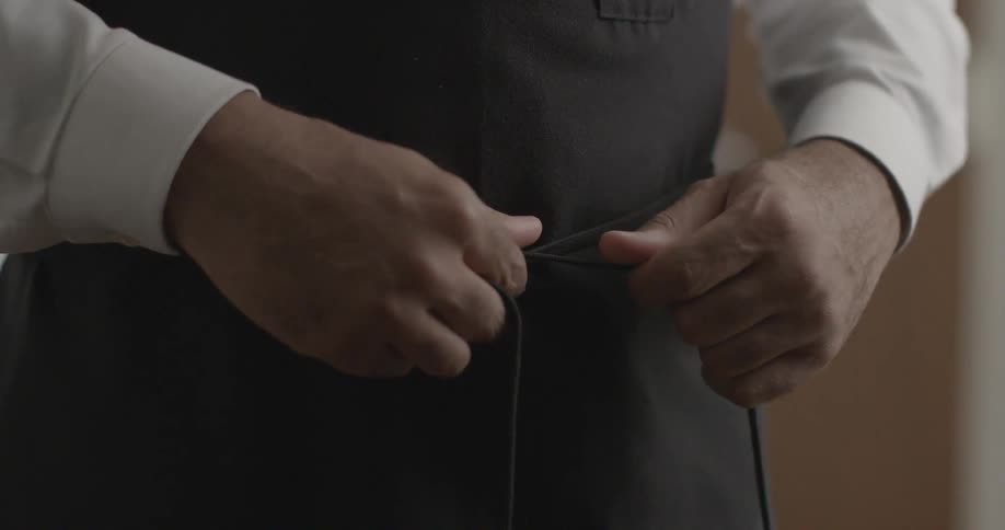 A man ties an apron around him