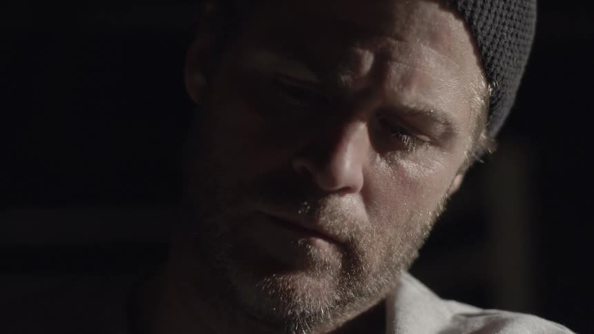 Man sitting and looking downwards in a dark room