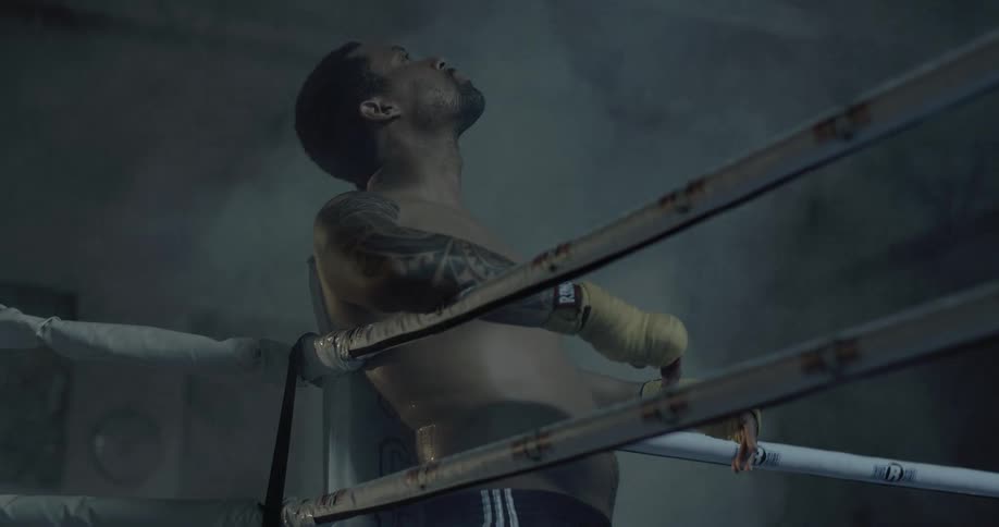 Man leans against the corner of boxing ring and rests his head back