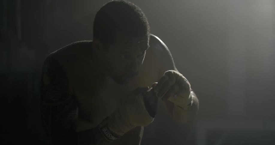 A man is shadowboxing in a dark area