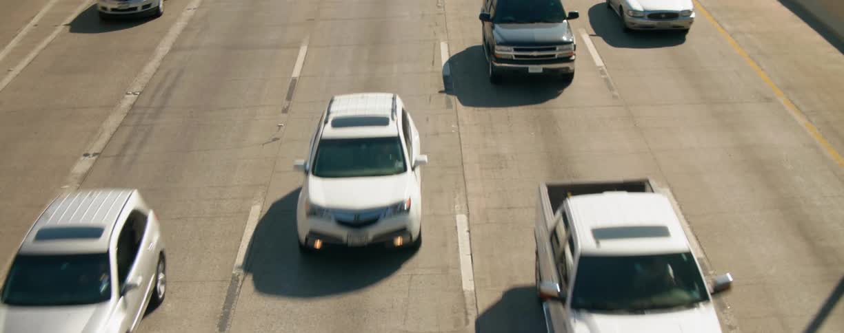 Traffic flows to and from city downtown past road signs and retaining walls