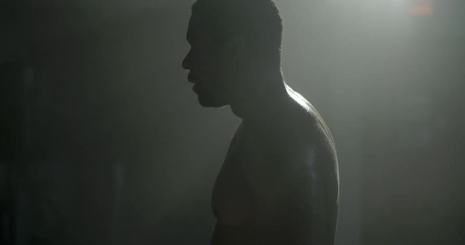 A man wipes sweat off his brow in a dark room