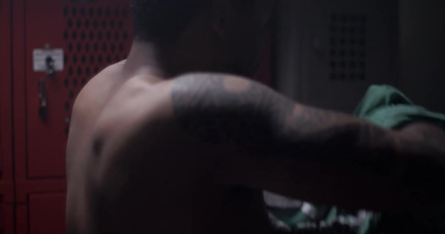 Man taking off his t-shirt in a locker room