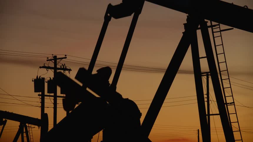 The oil rig is pumping at sunset