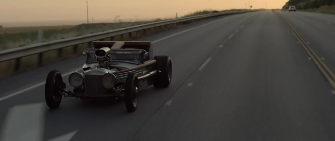 An old racing car weaves down a four lane highway