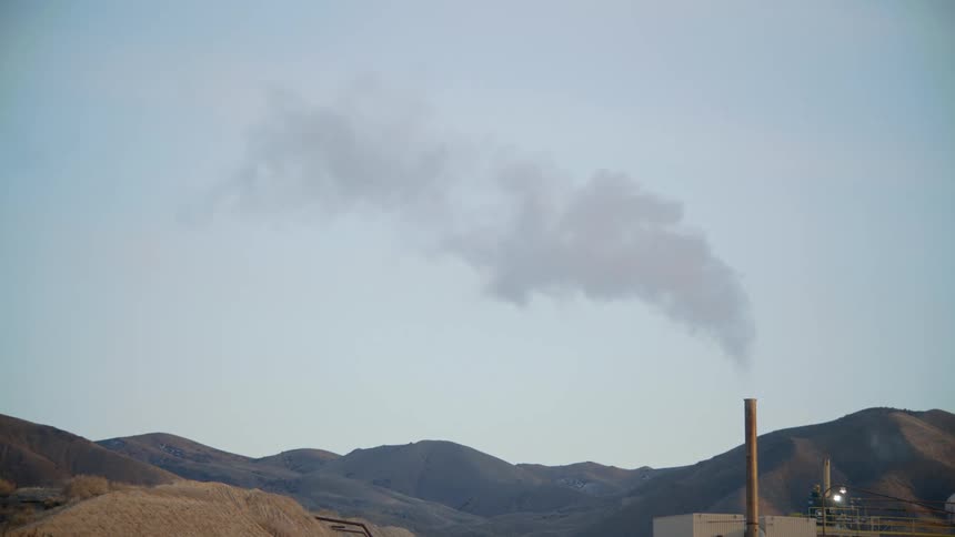 Smoke billowing out of a smoke stack on a factory