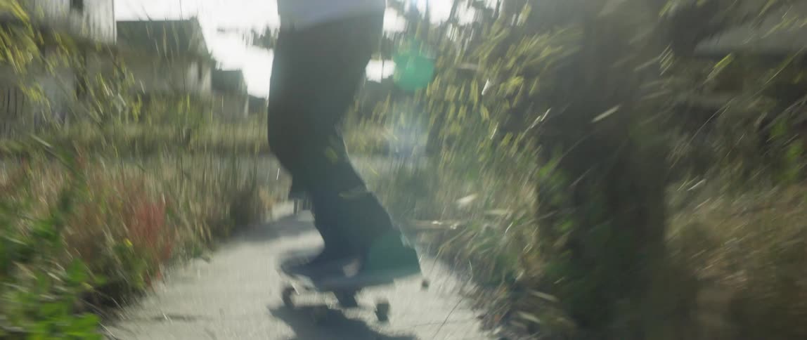 Two men with sneakers skateboard along a concrete path