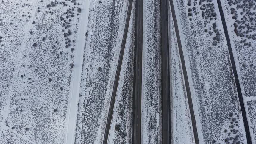 Roads with vehicles with fields with snow on the side