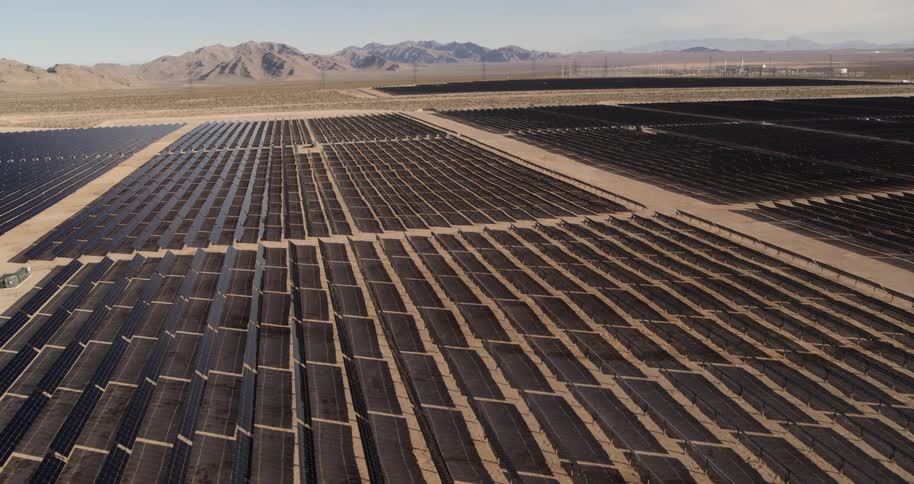 A solar farm with mountains and the sky in the background