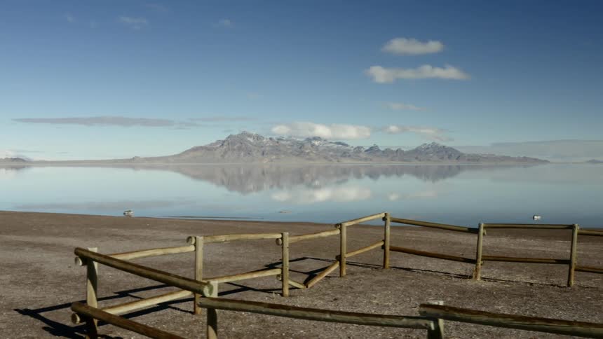 A wooden fence marks off a section of land on a vast ranch