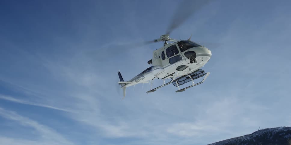 White helicopter takes off from snowy field