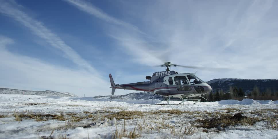 The helicopter sits running on the field