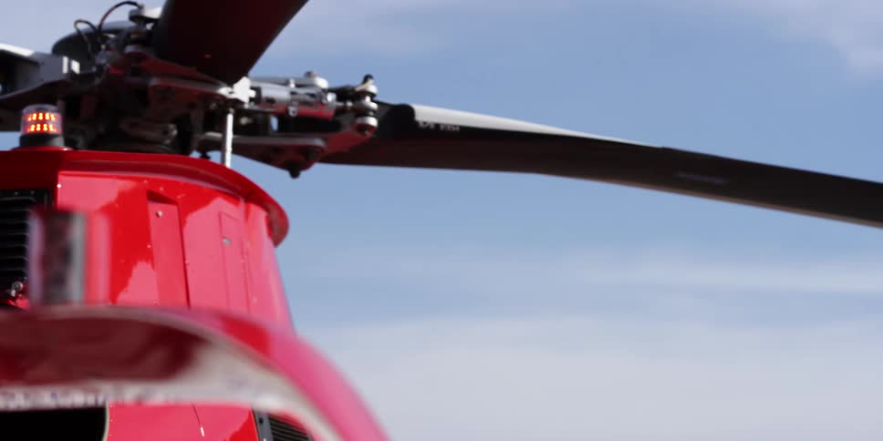 A helicopter rotor with the sky and mountains in the background