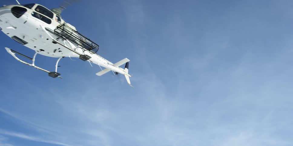 A helicopter hovers and then turns and flies off