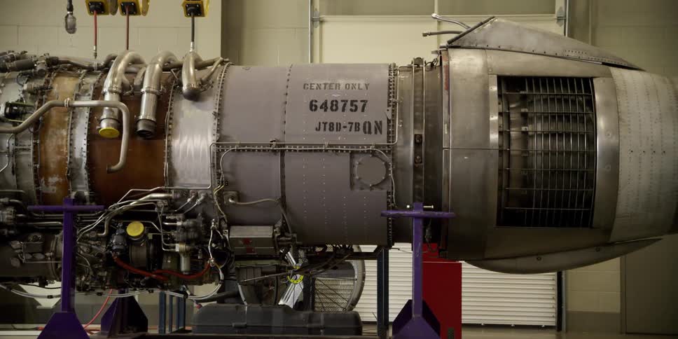A jet engine sits on a lift in a factory