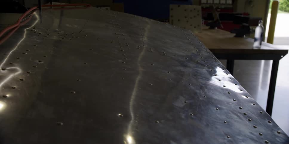 An airplane wing in a hangar with a table in the background