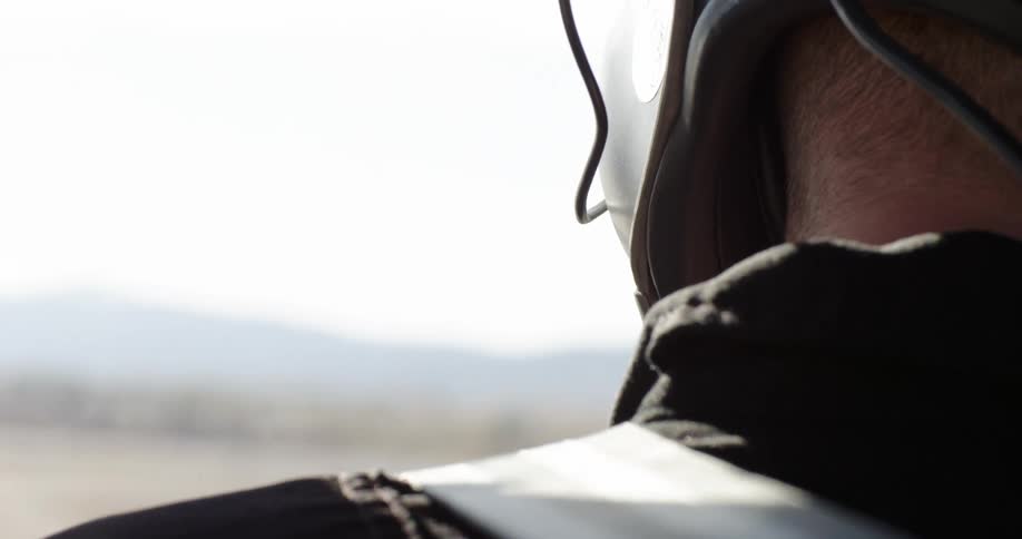 Man with a helmet on looks around as he stands outdoors