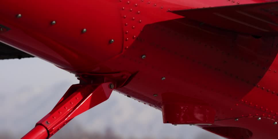 Part of a red metal aircraft sits outdoors