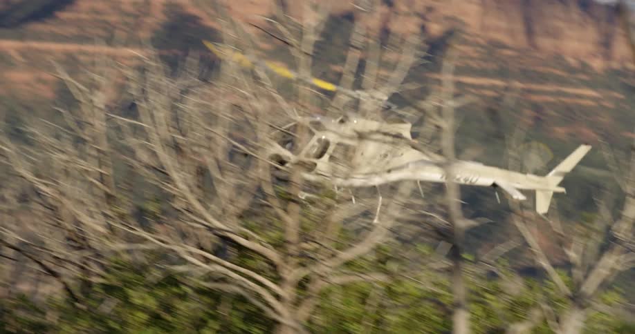 A helicopter flies by at a low altitude in a mountainous region