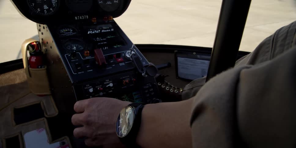A man operating the switches and dials of a helicopter from its cockpit
