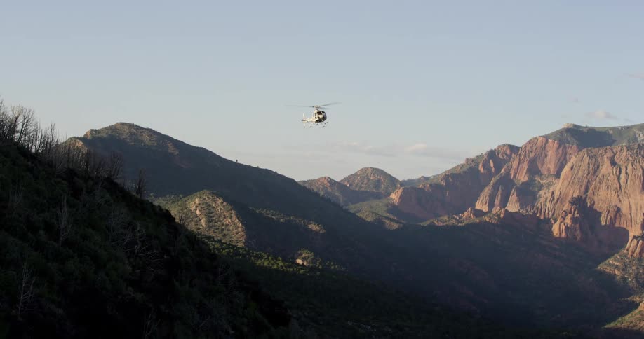 A helicopter is flying over a mountain range