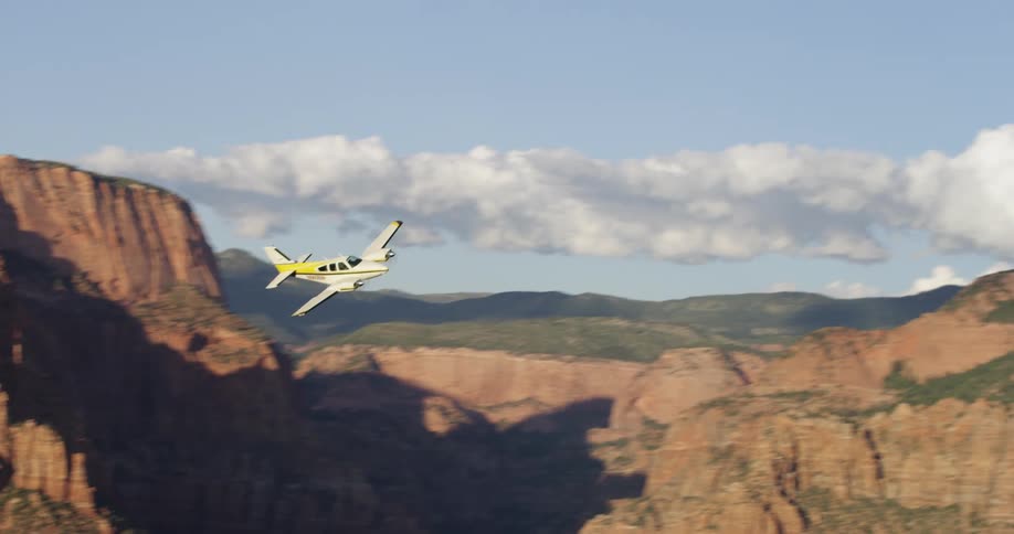 A jet plane flies between mountains