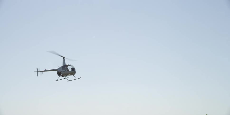 A helicopter flying in the sky over water with the city skyline in the background