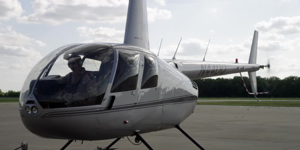 A man is sitting in a parked helicopter