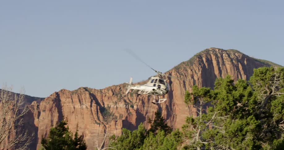 A helicopter flying past a canyon