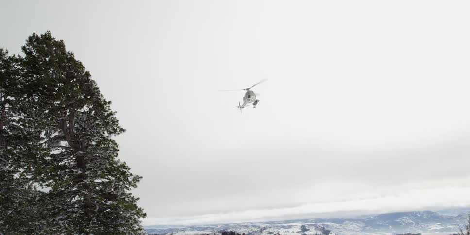 A helicopter is flying in the sky during winter