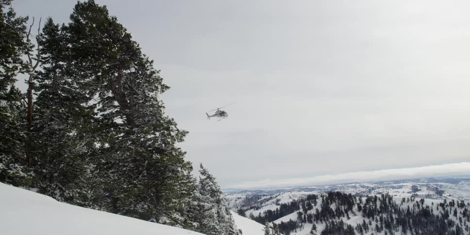 A helicopter flying over the snow covered mountains