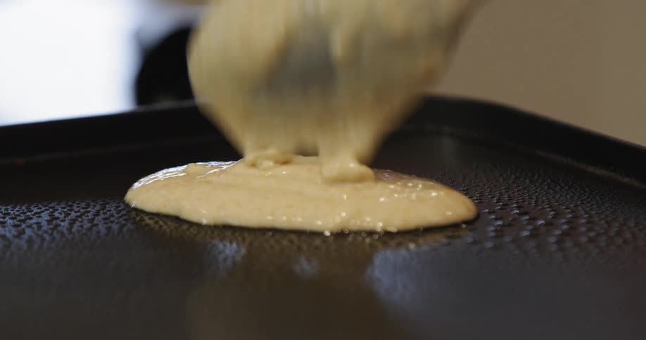 Batter being poured on skillet to make pancakes
