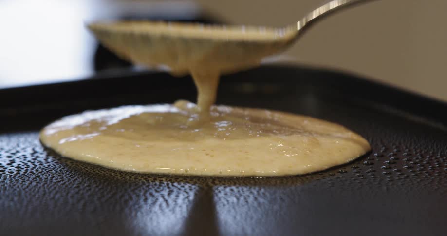 Pancake batter is poured and smoothed into a circle on a griddle