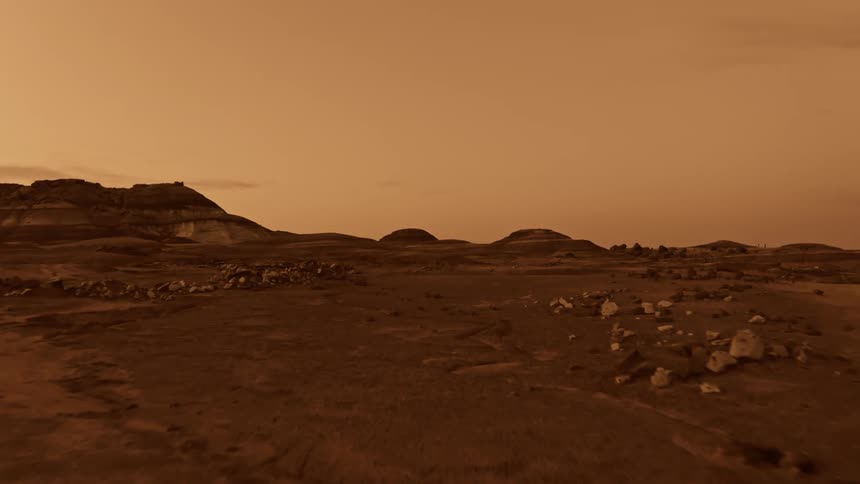 Rocks dot a large desert that leads to a canyon on another world