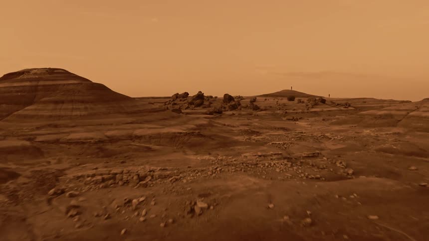Two people stand on a distant hill in the desert