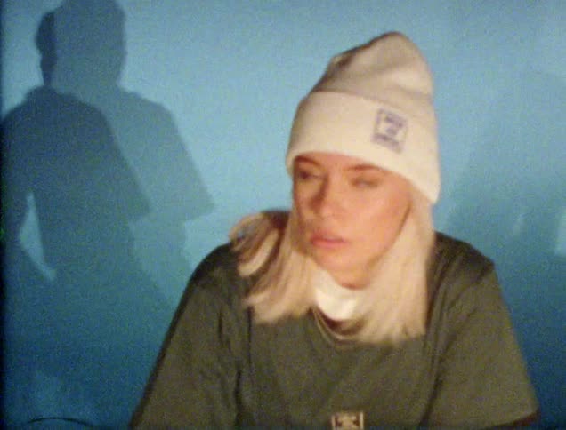 A woman with a hat sitting and looking around then staring