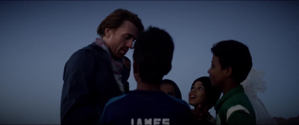 A white man stands and speaks to a family of middle eastern people