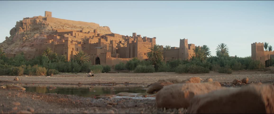 A person rides a horse past a large building