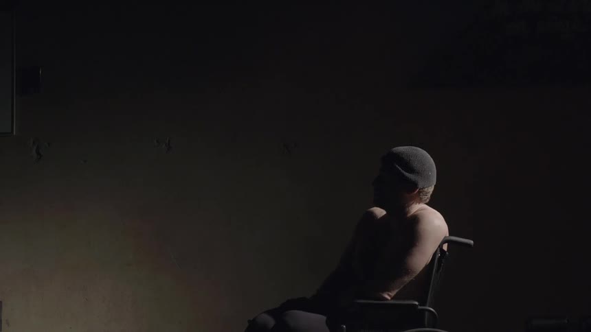 A man is sitting in a char covered in darkness