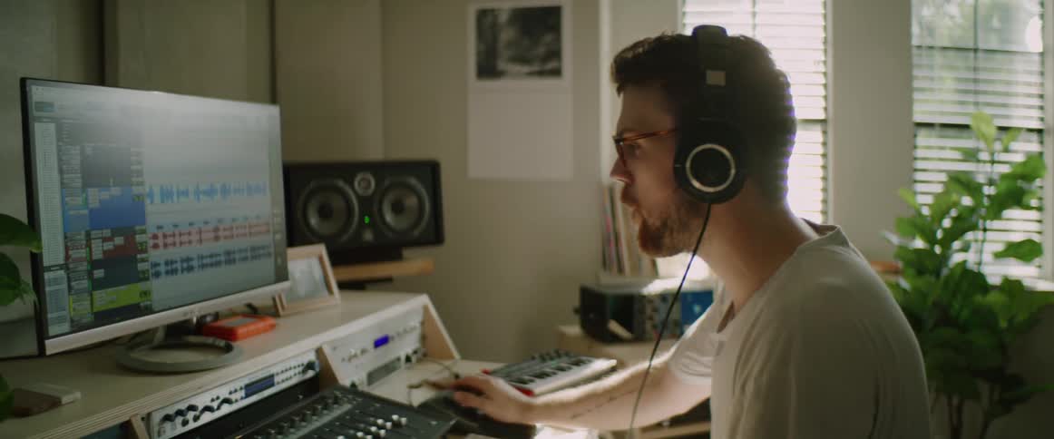 A white male puts on headphones and nods his head to music playing on a computer