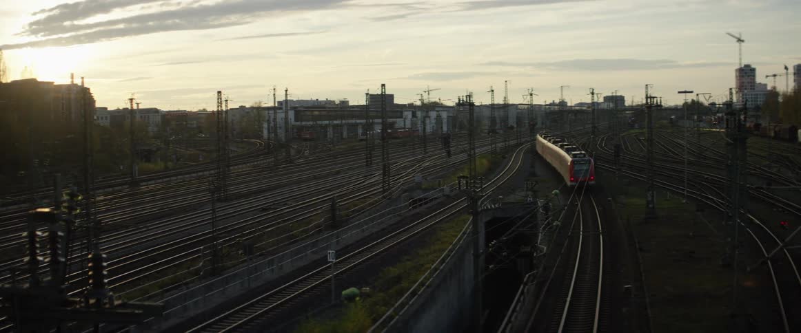 A train pulls out of a train yard with several empty tracks and transmission towers