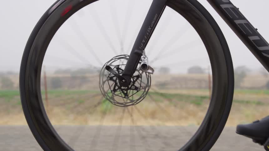 Close up of the wheel of a bicycle driving on a road near a field